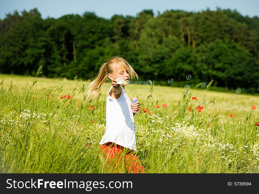 Little girl in a field making soap bubbles and having fun with it. Little girl in a field making soap bubbles and having fun with it