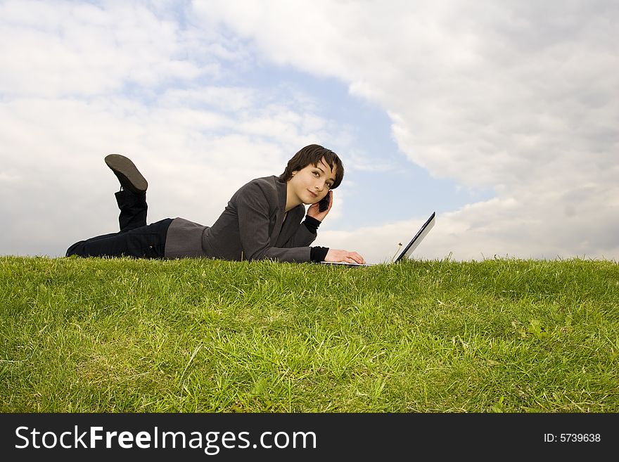 Girl with laptop sitting on the grass