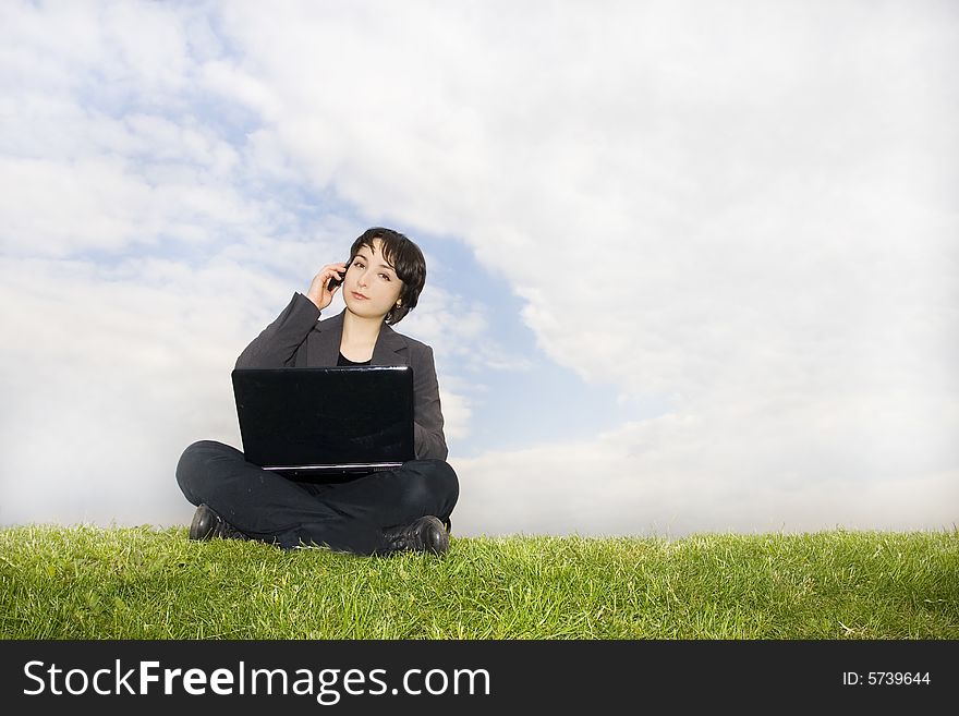 Girl with laptop sitting on the grass