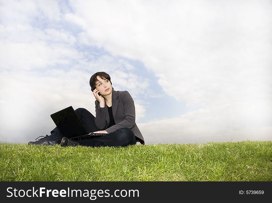 Girl with laptop sitting on the grass