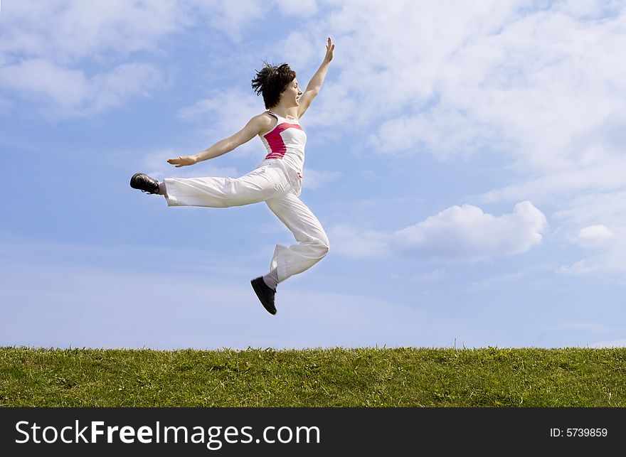 Happy girl with open arms jumping on the grass. Happy girl with open arms jumping on the grass