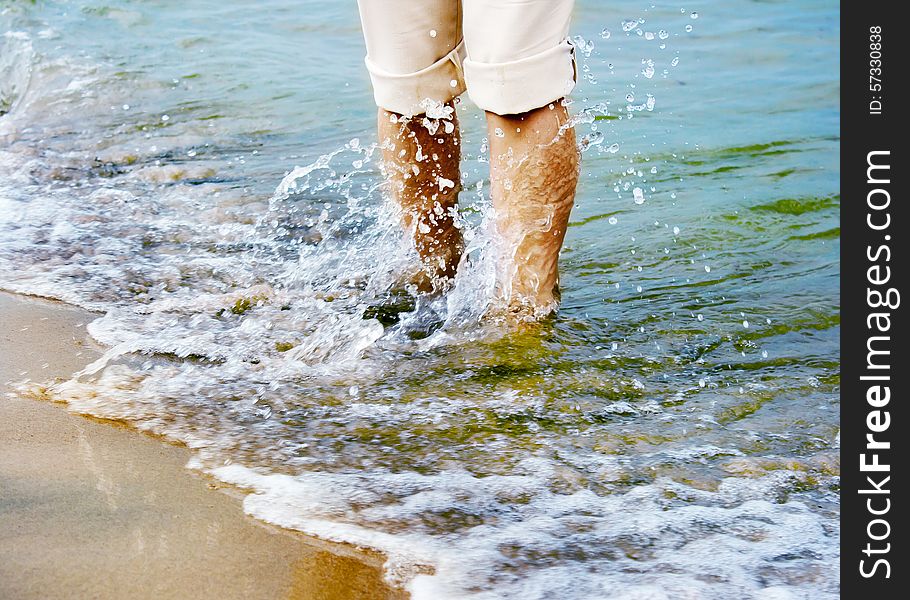 Female legs sweeping sea wave. close-up. Female legs sweeping sea wave. close-up