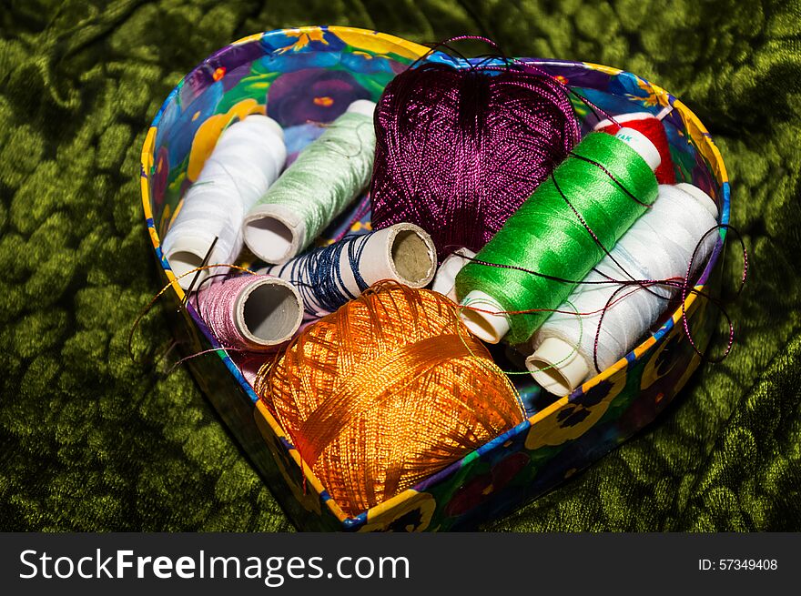 Colorful box with floral cover full of colorful spools of thread. Colorful box with floral cover full of colorful spools of thread