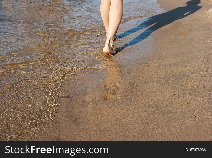Barefoot woman walking on the sea shore on summer closeup. Barefoot woman walking on the sea shore on summer closeup