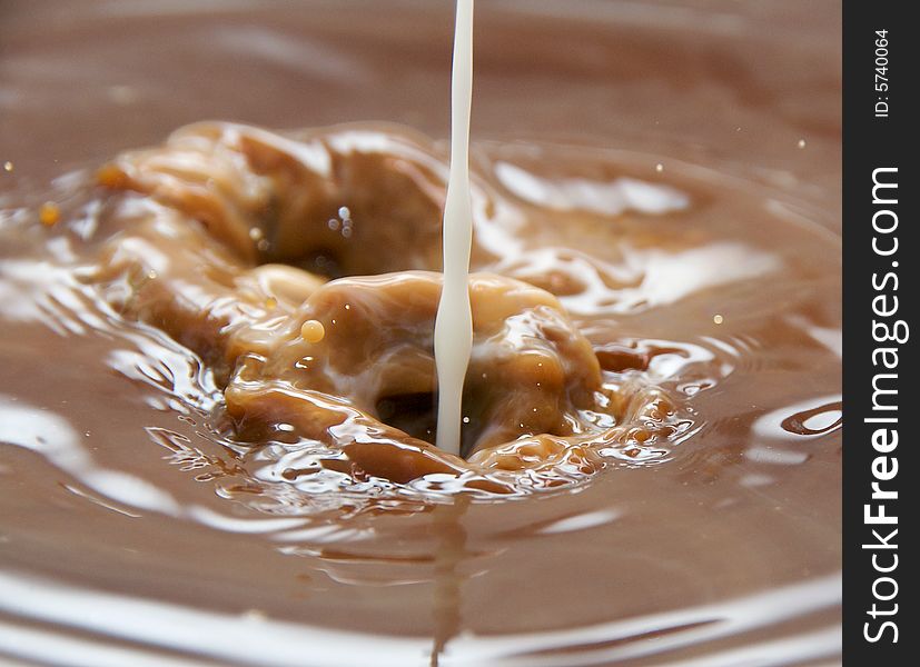 Milk pouring into coffee or hot chocolate