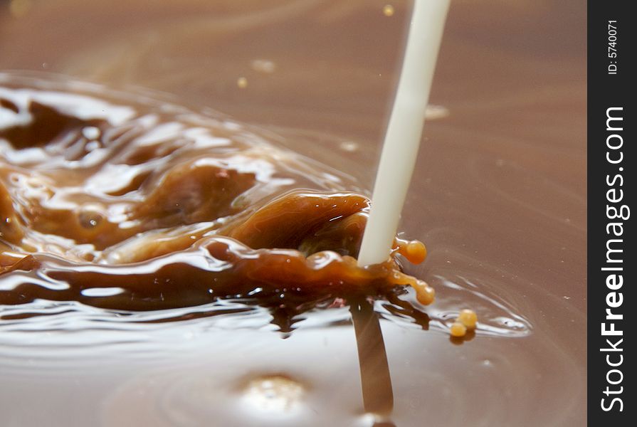 Milk pouring into coffee or hot chocolate