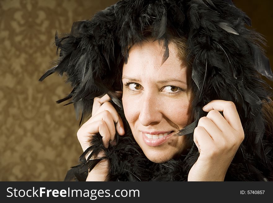 Pretty Hispanic Woman Wearing a Feather Boa in front of Gold Wallpaper. Pretty Hispanic Woman Wearing a Feather Boa in front of Gold Wallpaper