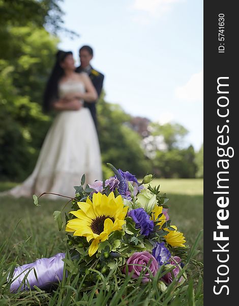 Wedding bouquet with bride and groom in background