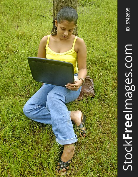 A Indian woman with a laptop in a park. A Indian woman with a laptop in a park.