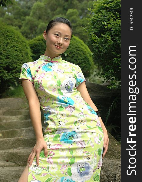 Chinese girl standing on stone-made stairs in park, wearing traditional Chinese dress - QiPao. Chinese girl standing on stone-made stairs in park, wearing traditional Chinese dress - QiPao.