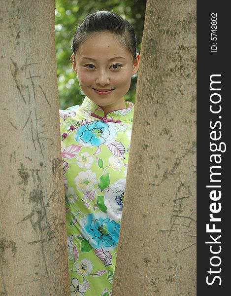 Charming girl standing between branches of tree in park. Charming girl standing between branches of tree in park.