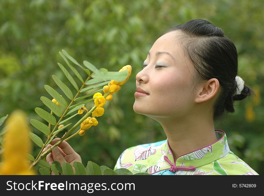 Chinese girl smelling flowers in park, wearing traditional Chinese dress. Chinese girl smelling flowers in park, wearing traditional Chinese dress.