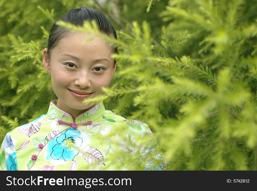 Chinese girl smiling, standing in park between trees. Chinese girl smiling, standing in park between trees.