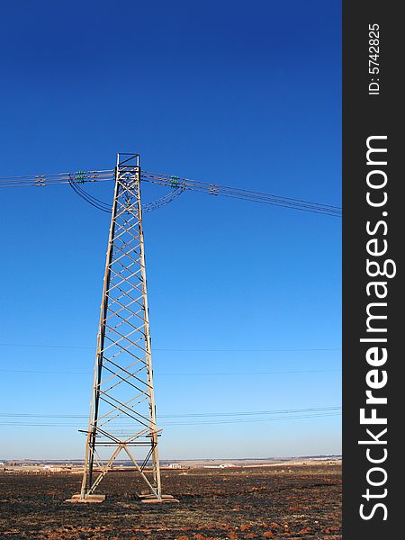 Tall electricity pylon against bright blue sky background. Tall electricity pylon against bright blue sky background
