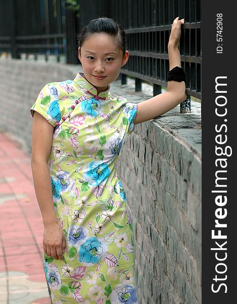 Young Chinese girl standing on sidewalk, wearing traditional Chinese dress. Young Chinese girl standing on sidewalk, wearing traditional Chinese dress.