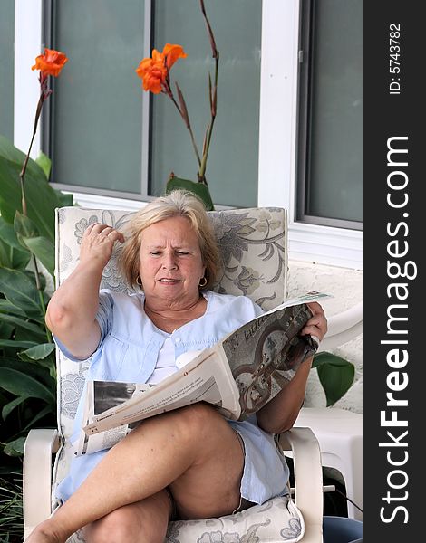 Photo of a senior reading the latest news in the newspaper outdoor in the patio. Photo of a senior reading the latest news in the newspaper outdoor in the patio