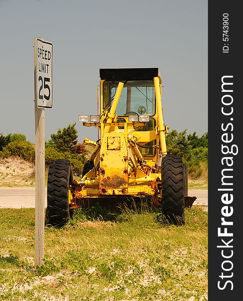 A bulldozer at a construction site with a speed limit sign. A bulldozer at a construction site with a speed limit sign