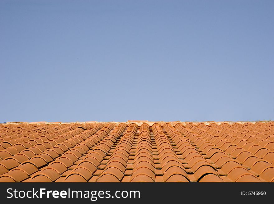 A roof of red quarry tiles against a blue sky. A roof of red quarry tiles against a blue sky