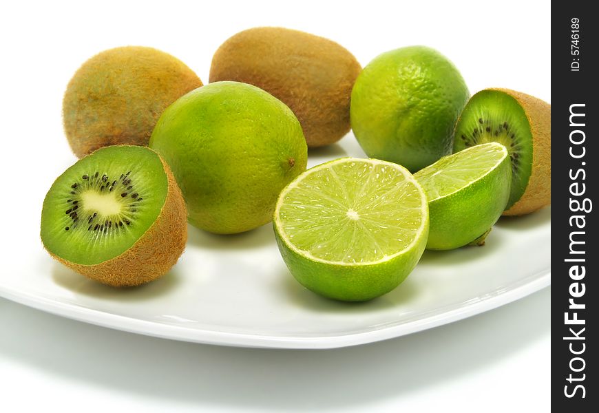 A group of fresh kiwis and limes on a white plate and isolated on white background. A group of fresh kiwis and limes on a white plate and isolated on white background