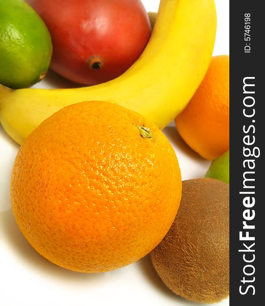 Fresh limes, kiwis, mango, banana and oranges placed on a white table. Fresh limes, kiwis, mango, banana and oranges placed on a white table