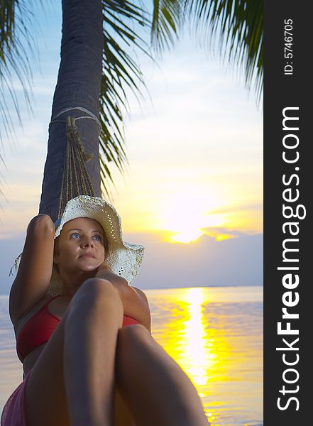 View of a woman lounging in hammock during sunset