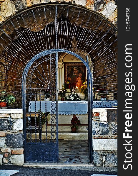 Gate opening in front of an old Italian chapel