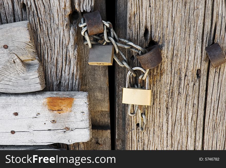 Two locks with chain on wooden rotting door