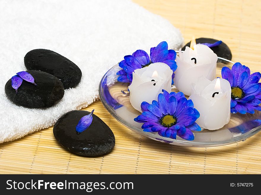 Candles in water with blue flowers and towel