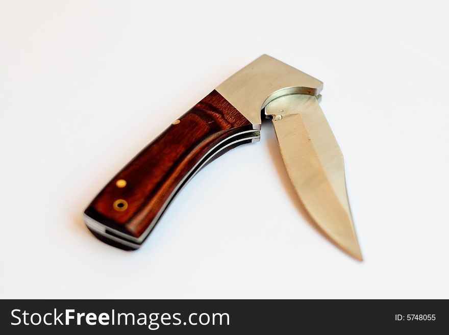 A fierce looking foldable knife, shot from above on a white background, half open.