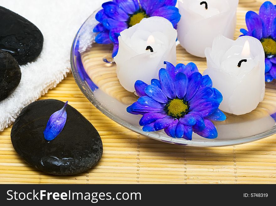 Candles in water with blue flowers and towel