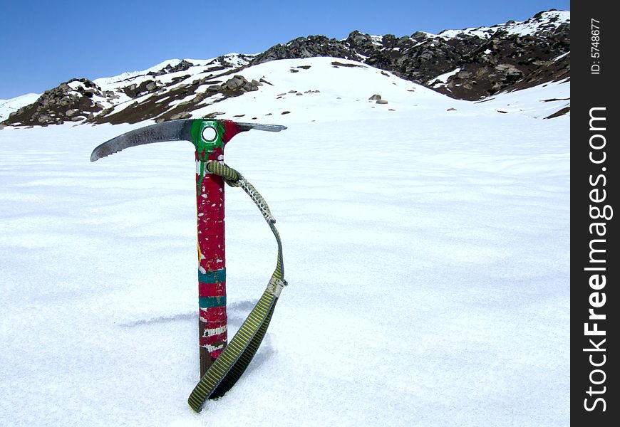 Ice-axe in snow against mountain background