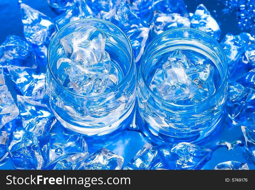 Glasses with water and ice over blue