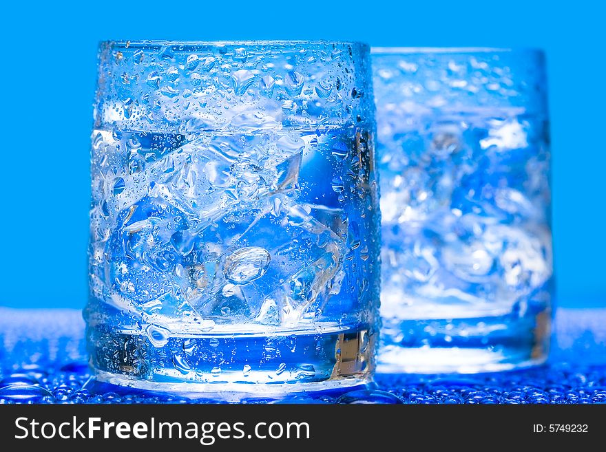 Glass with water and ice over blue