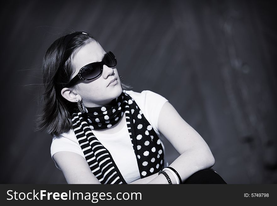 A serious preteen girl looking into the distance through dark sunglasses. B&W image. A serious preteen girl looking into the distance through dark sunglasses. B&W image.