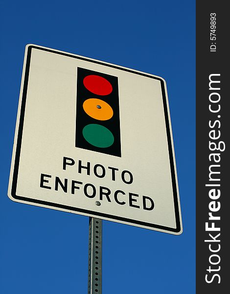 A photo enforced sign in front of a blue sky.