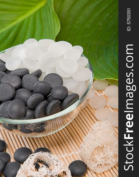 White and black stones lay in a vase on a mat with a green leaf