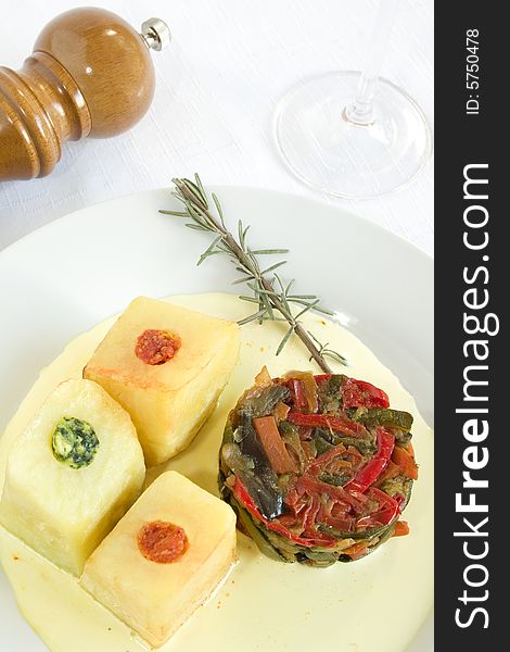 A dish with ratatouille and stuffed potatoes (spinach, tomato, cheese) on a soft saffron cream. Focus on vegetables. A dish with ratatouille and stuffed potatoes (spinach, tomato, cheese) on a soft saffron cream. Focus on vegetables.