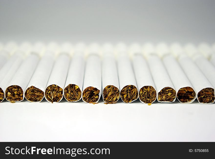 Cigarettes arranged in line on a white background. Cigarettes arranged in line on a white background