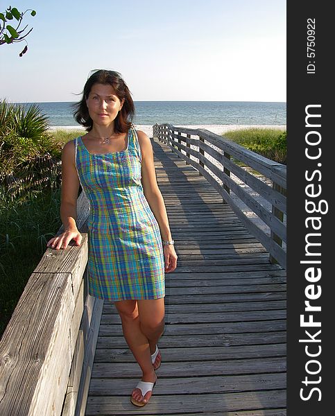 The girl waiting on a wooden path that leads to Sanibel Island beach (Florida). The girl waiting on a wooden path that leads to Sanibel Island beach (Florida).