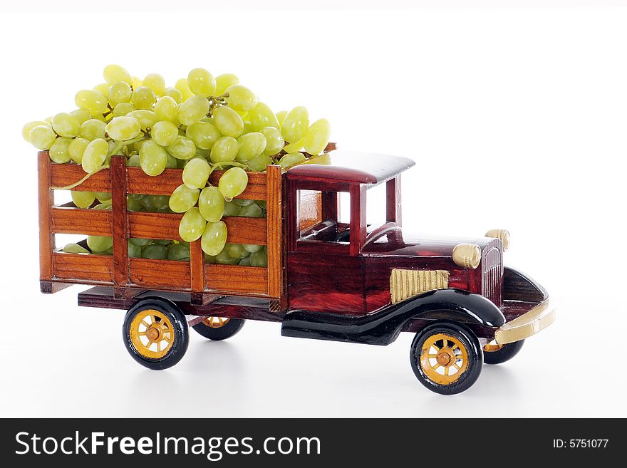 A vintage, wooden, model, pickup truck overflowing with real bunches of juicy green grapes. A vintage, wooden, model, pickup truck overflowing with real bunches of juicy green grapes.