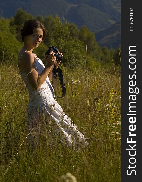 Woman in white holding a camera in the middle of the mountains