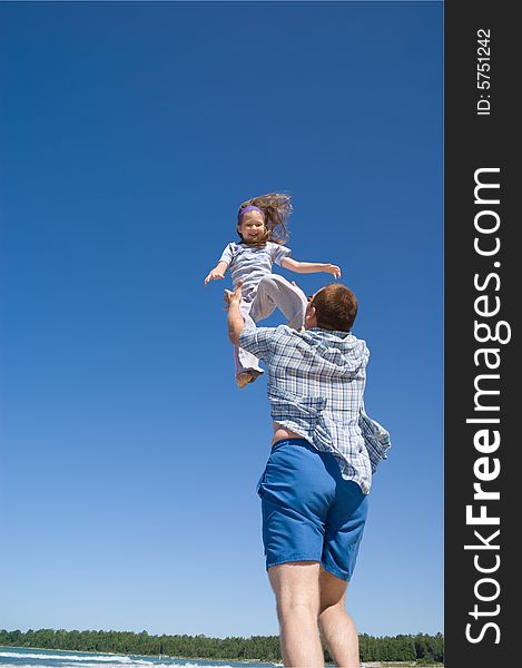 A father throws his little girl into the air. A father throws his little girl into the air