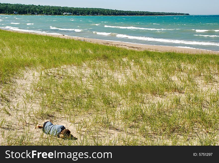Man dreaming on dune, lake shore.