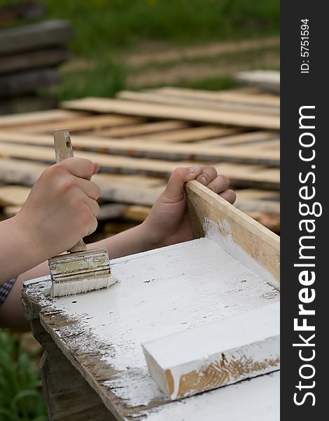 Photo of painter painting wood construction with white paint