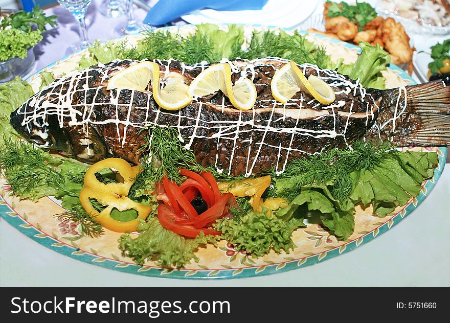 Roasted sea fish with lemon, tomatoes, lettuce on table. Roasted sea fish with lemon, tomatoes, lettuce on table.