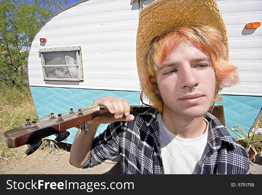 Young Man with Bright Red Hair and a Guitar in front of Trailer. Young Man with Bright Red Hair and a Guitar in front of Trailer