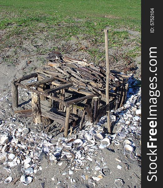 House of sticks on the beach with shells. Three little pigs house. House of sticks on the beach with shells. Three little pigs house.