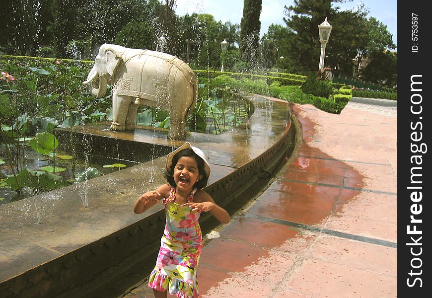 A little girl child filled with excitement in the garden near the water fountains. A little girl child filled with excitement in the garden near the water fountains