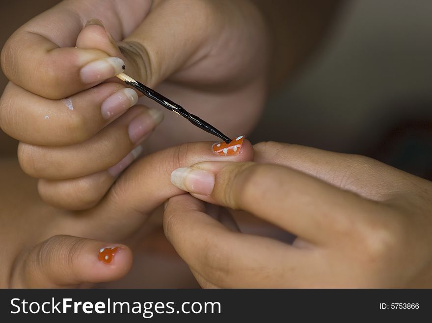 Hand of a woman with long nails, painting the nails of another woman red with black and blue spots. Shallow depth of field. Hand of a woman with long nails, painting the nails of another woman red with black and blue spots. Shallow depth of field.