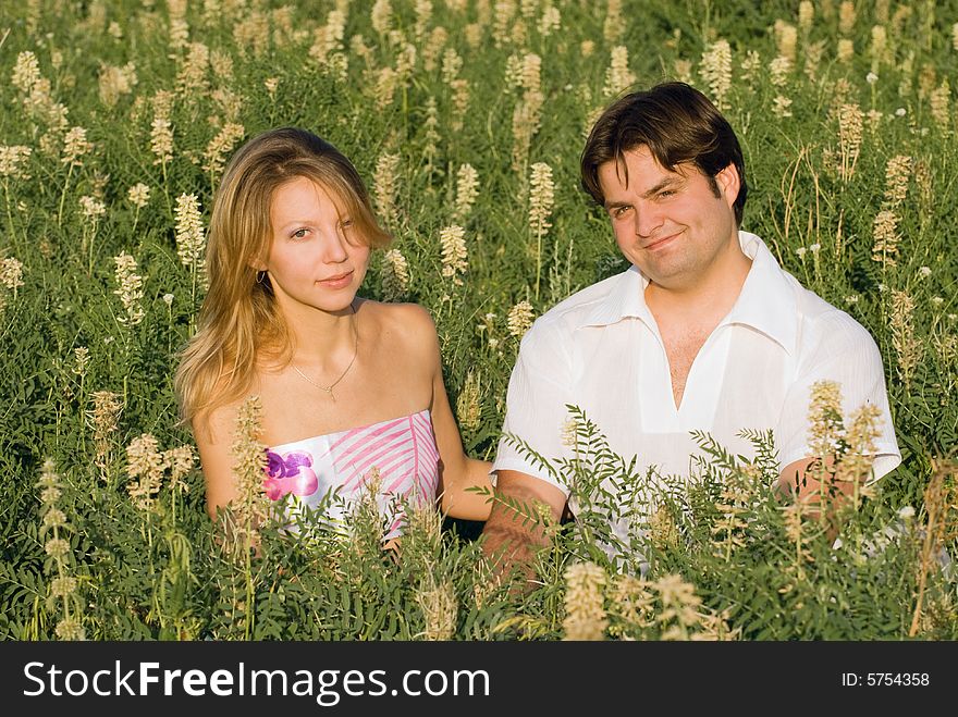 Happy couple sitting in the grass enjoying being together